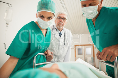 Doctors looking at a patient while leaning on a bed