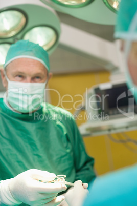 Surgeon receiving scissors from a colleague