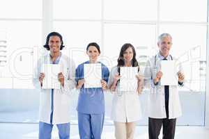 Four medical people standing upright while holding blank sheets