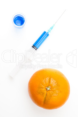 Syringe between a beaker and an orange