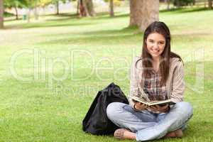 Smiling teenager sitting while holding a textbook