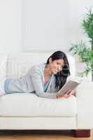Smiling woman reading a book while she lays on a couch