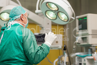 Surgeon wearing surgical equipment raising his arm