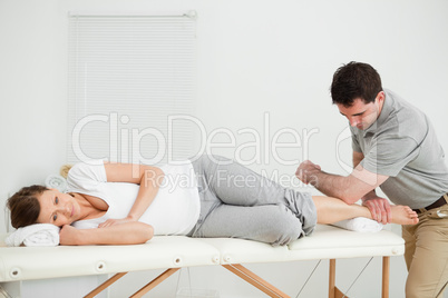 Doctor manipulating the leg of his patient while using his elbow