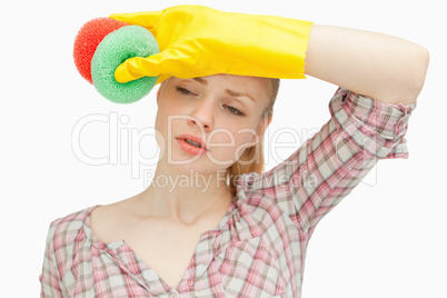 Woman wiping her forehead while holding sponges