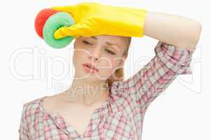 Woman wiping her forehead while holding sponges