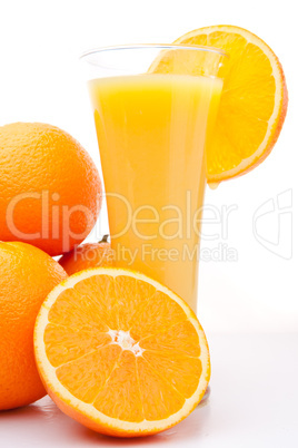 Pile of oranges near a glass of orange juice