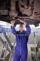 Concentrated mechanic repairing a car with spanners