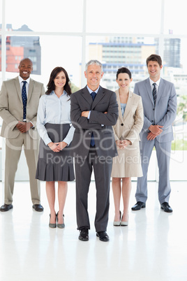 Smiling mature director crossing his arms in front of his team