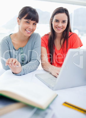 Close up shot of a girl and her friend smiling as they sit with