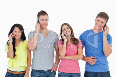 A smiling group of friends make calls while looking into the cam