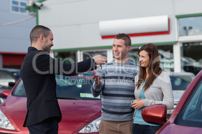 Salesman giving car keys to a couple