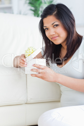 Woman opening a gift box while sitting on the floor in front of