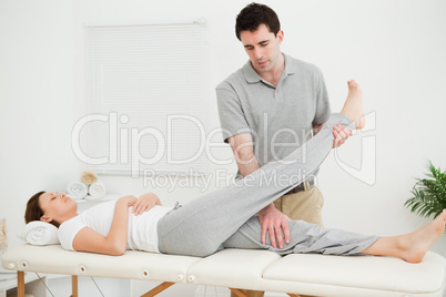 Brunette physiotherapist raising the leg of a patient