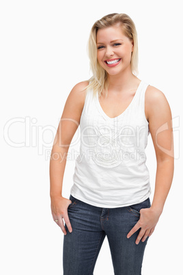 Laughing blonde woman standing with her thumbs in her pockets