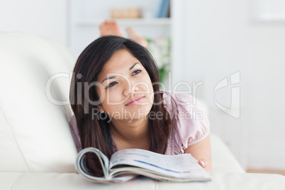 Woman lays on a sofa while reading a magazine
