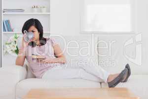 Drinking woman lying on a couch