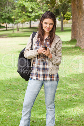 Young student posing while using a smartphone