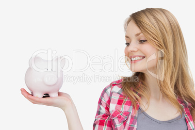 Woman looking at a piggy bank on her hand