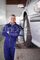 Front view of a mechanic smiling next to a car