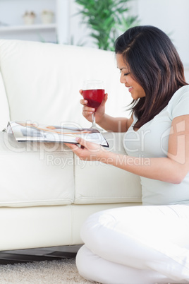 Smiling woman on her knees holding a glass of red wine and holdi