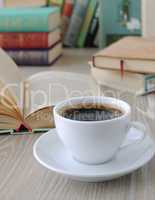 cup of coffee on a table with books.