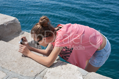 Teenage girl taking photos by the sea