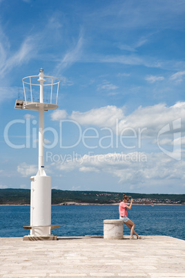 Teenage girl taking photos by the sea