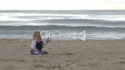 Young happy mother plays with her son on the beach.