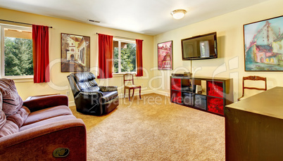 Tv living room with art and red curtains and beige carpet.
