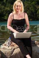 Junge Frau am See mit Laptop