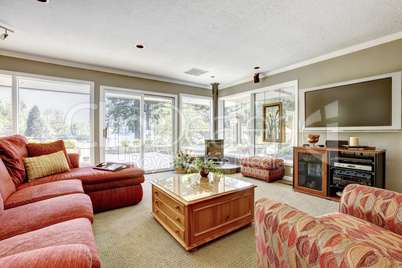 Living room with red sofa, beige walls and many windows.