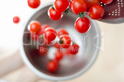 Cherry Tomatoes Tumbling From Metal Colander Into Metal Pan