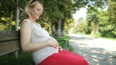 pregnant woman sitting on park bench