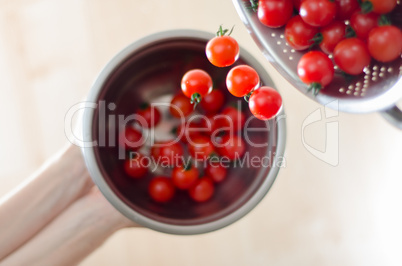 Cherry Tomatoes Tumbling From Metal Colander Into Metal Pan