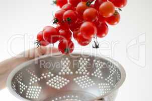 cherry tomatoes tumbling into metal colander