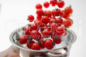 cherry tomatoes tumbling into metal colander