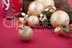 Weihnachtliche Dekoration mit goldenen Kugeln und Tanne auf rote
