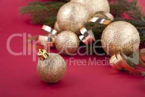 Weihnachtliche Dekoration mit goldenen Kugeln und Tanne auf rote