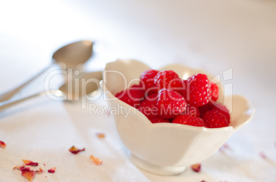 Cream pouring from a jug over fresh rasberries