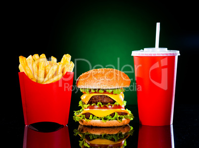 Tasty hamburger and french fries on a dark green