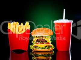 Tasty hamburger and french fries on a dark green