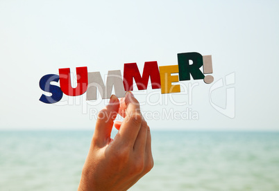 Female's hand holding colorful word "Summer"