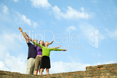 Three young people staying with raised hands