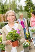 Senior woman hold potted flower garden store