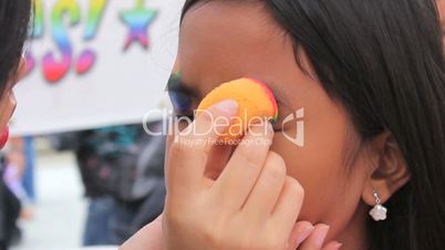Asian Girl Getting A Rainbow Face Painting Mask Applied