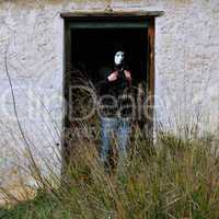 masked figure and broken door