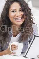Woman Smiling Drinking Tea or Coffee Using Tablet Computer