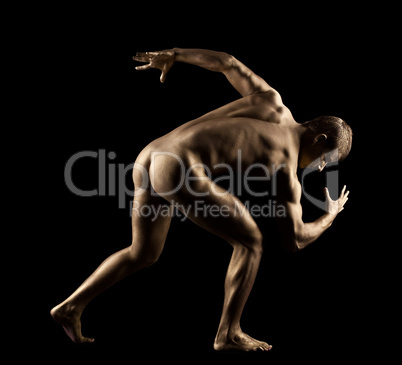 Athletic man posing nude in dark