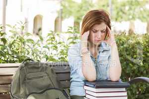 Female Student Outside with Headache Sitting with Books and Back